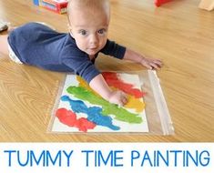 a baby laying on the floor playing with some paint