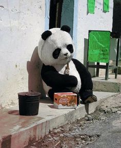 a giant panda bear sitting on the side of a building next to a can of coke