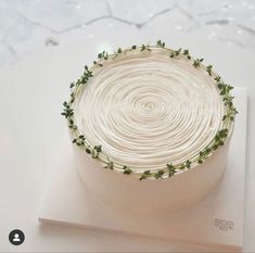 a white cake with green sprigs on it sitting on top of a table