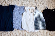 four women's tops are lined up on the floor, all in different colors