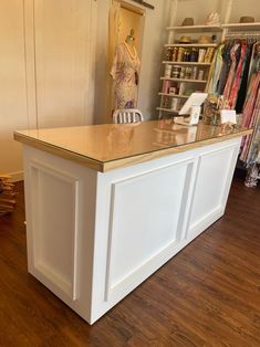 a white counter top sitting inside of a store next to a shelf filled with clothes