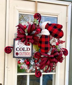 a red and black plaid christmas wreath hanging on the front door of a house with a sign that says cold outside