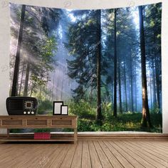 a wall hanging in a room with a large tapestry on it's side that has trees and sunlight coming through the forest