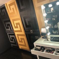 a vanity with a mirror and lights on it in a room that has black walls