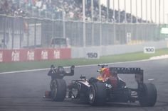 a red and black race car driving on a track with people watching from the stands