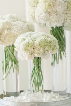 three vases filled with white flowers on top of a table