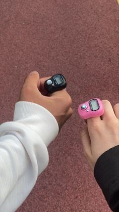 two people holding cell phones in their hands, one is pink and the other is black