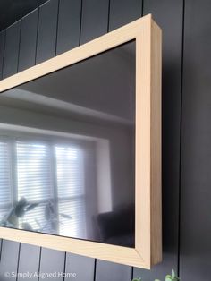 a mirror hanging on the side of a wall next to a potted plant and window