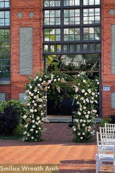 a white chair sitting in front of a building with flowers on it's side