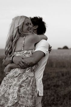 black and white photograph of two women hugging each other in front of an open field