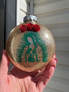 a hand holding an ornament with roses on it