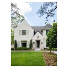 a large white house with lots of windows and grass in front of the house is surrounded by trees