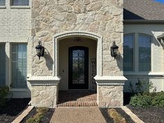 the front entrance to a house with two lights on each side and an iron door