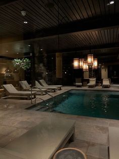 an indoor swimming pool with lounge chairs around it