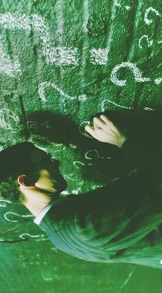 a man writing on the side of a wall with his hands and head above water