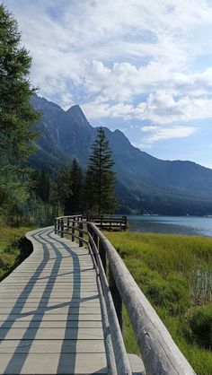 a wooden walkway leading to a lake with mountains in the background