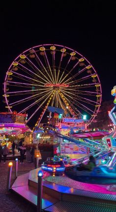 an amusement park at night with ferris wheel and rides