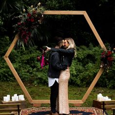 a man and woman are kissing in front of a hexagonal frame with candles