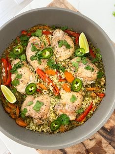 a pan filled with rice and vegetables on top of a wooden table next to limes