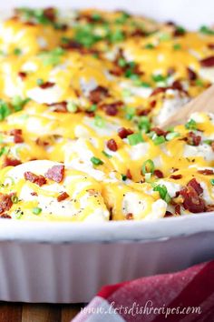 a casserole dish with bacon, cheese and green onions