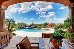 an outdoor patio with chairs and tables next to a pool