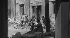 an old black and white photo of people in front of a building with rubble on the ground