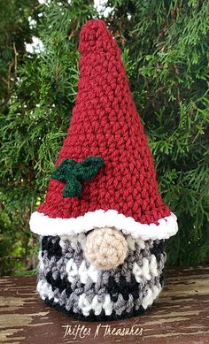 a crocheted santa hat sitting on top of a wooden table next to a tree