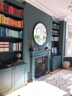 a living room with bookshelves and a mirror on the wall next to a fireplace