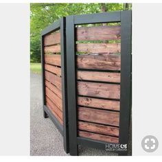 a wooden fence with black slats on the top and bottom part, in front of some trees