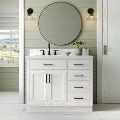 a bathroom vanity with a round mirror above it