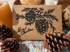 a card with pine cones on it next to some candles and other holiday decor items