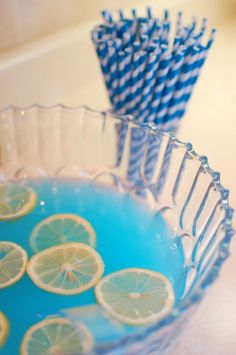 blue and white striped straws in a bowl with lemon slices on the rim,