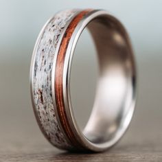 a wedding ring with antler wood inlays the center, on a wooden table