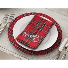 a red plaid table cloth with the word merry written on it sits next to a white plate and silverware