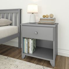 a nightstand with books on it next to a bed