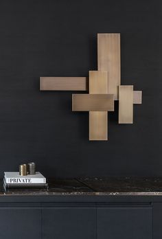 a table with a book, candle and sculpture on it in front of a black wall