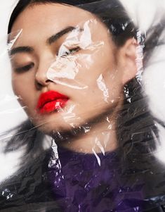 a woman with her eyes closed and red lips wrapped up in plastic wrap over her face