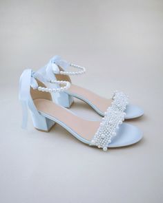 a pair of blue shoes with pearls on the toe and heels are sitting on a white surface