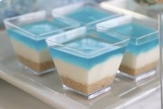 four desserts are arranged on a plate with blue and white icing in the middle