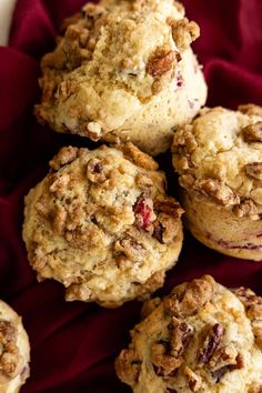 several muffins with cranberries and pecans in the middle on a red cloth