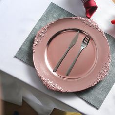 a pink plate with a fork and knife sitting on top of it next to a napkin