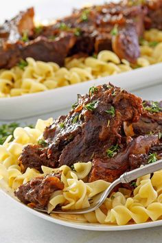 two white plates filled with pasta and meat