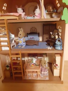 a doll house with furniture and accessories in the living room, including two rabbits sitting on chairs