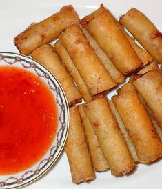 some fried food on a plate next to a bowl of red sauce and dipping sauce