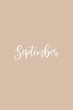 the word september written in white ink on a beige background