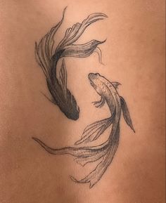 a woman's back with a tattoo of two fish on the side and one in the middle