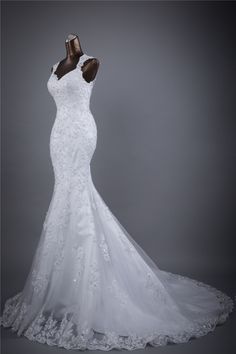 a wedding dress on display in front of a gray background