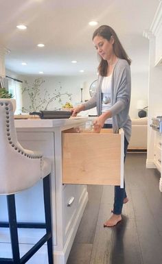 a woman standing in a kitchen holding a wooden box