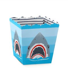 a box shaped like a shark with a striped shirt on it's chest and mouth