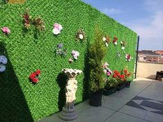 an artificial grass wall with flowers and statues on the top floor next to each other